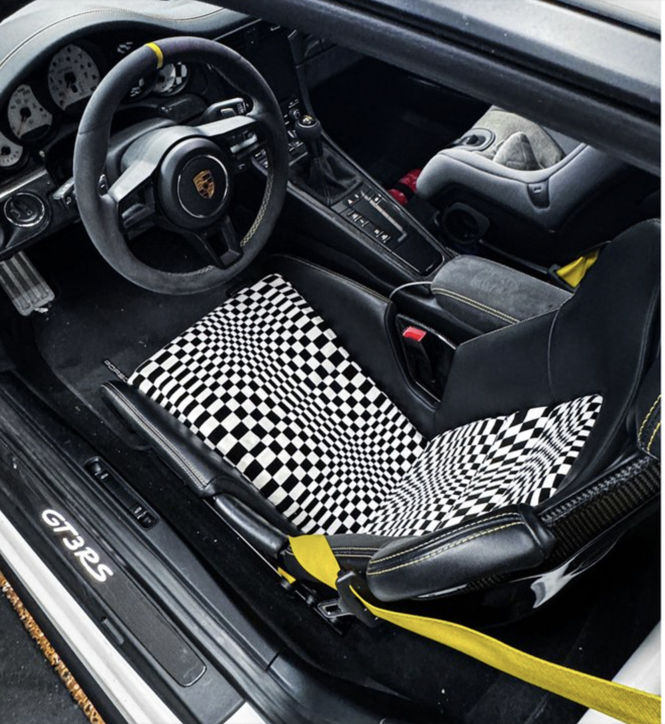 Porsche 991 GT3 RS carbon bucket seat with warped black-and-white checker insert and yellow harness