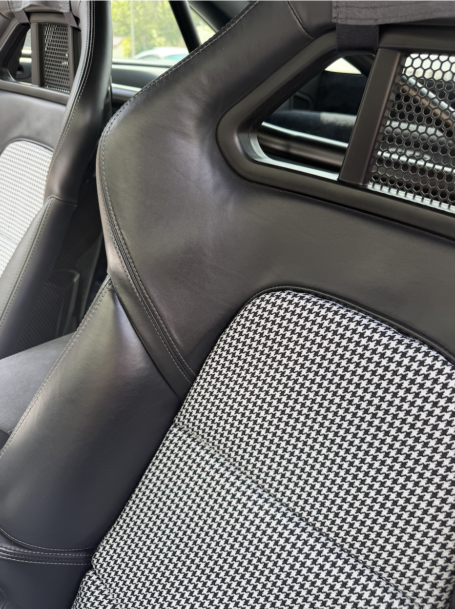 Close detail of houndstooth fabric insert against black leather bolster with contrast stitching
