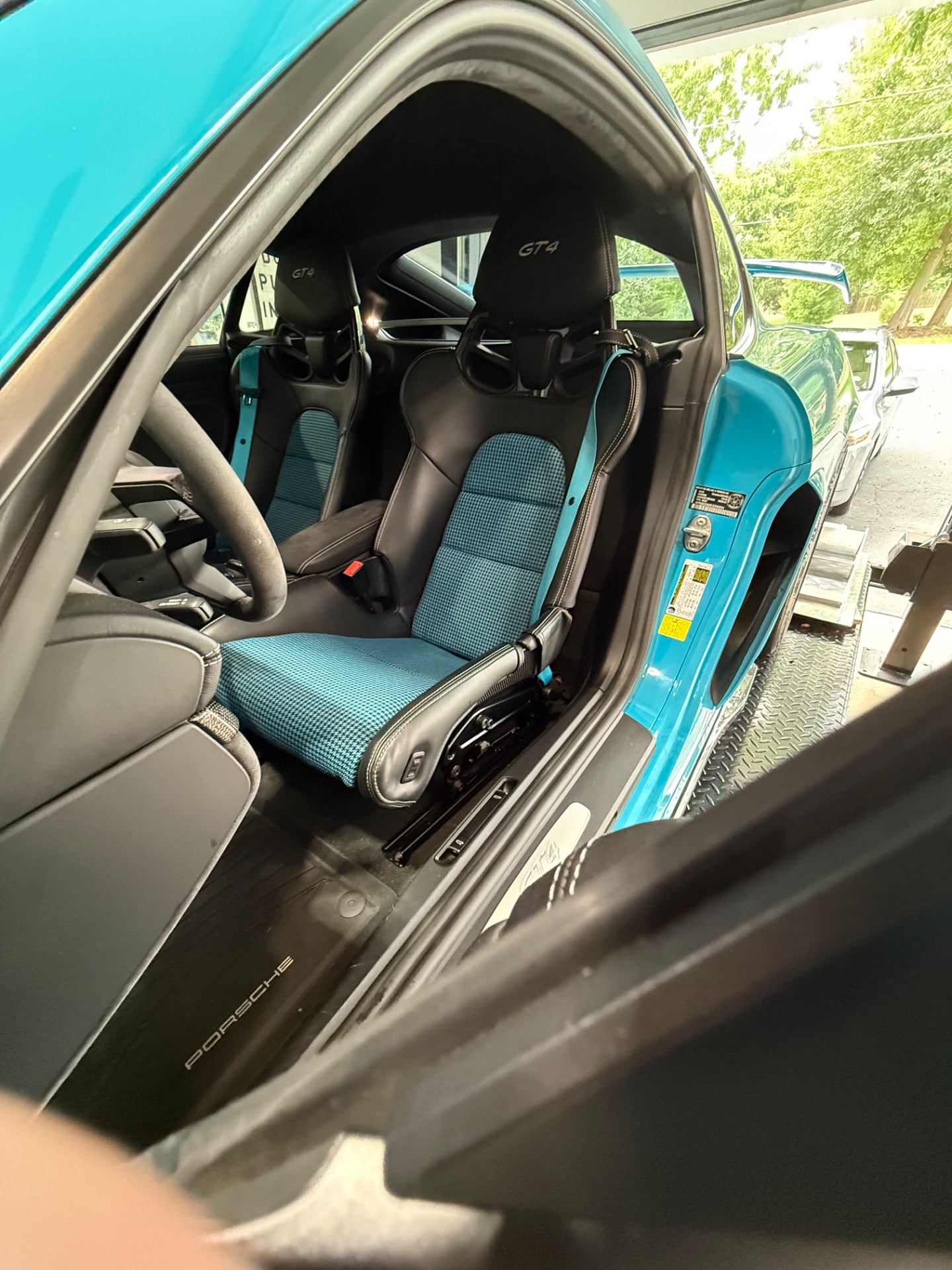 Miami Blue Porsche 718 GT4 seen through the open door showing blue houndstooth seat centers