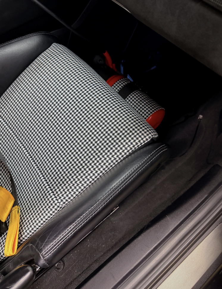 Houndstooth fire extinguisher cover beside a Porsche GT4 seat